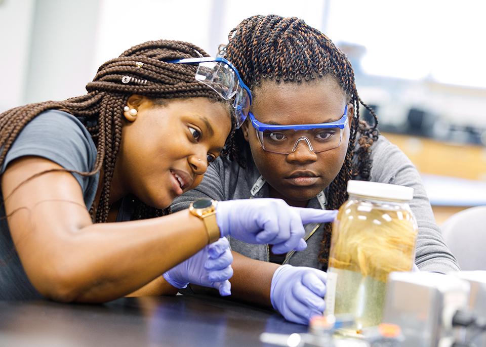 2 female students observe jar in lab class